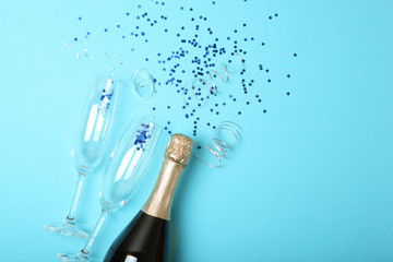 Champagne bottle, glasses and confetti on a colored background top view. Concept holiday, birthday,...