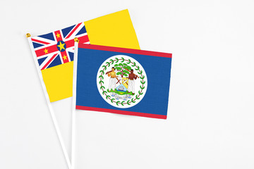 Belize and Niue stick flags on white background. High quality fabric, miniature national flag. Peaceful global concept.White floor for copy space.