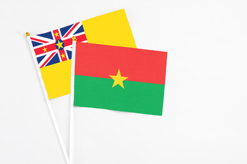 Burkina Faso and Niue stick flags on white background. High quality fabric, miniature national flag. Peaceful global concept.White floor for copy space.
