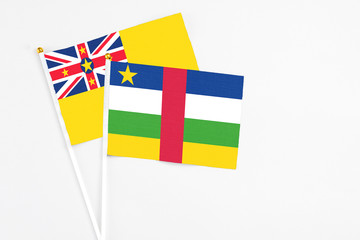 Central African Republic and Niue stick flags on white background. High quality fabric, miniature national flag. Peaceful global concept.White floor for copy space.