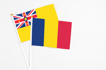 Chad and Niue stick flags on white background. High quality fabric, miniature national flag. Peaceful global concept.White floor for copy space.