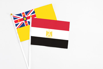 Egypt and Niue stick flags on white background. High quality fabric, miniature national flag. Peaceful global concept.White floor for copy space.