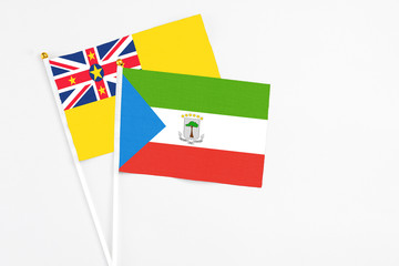 Equatorial Guinea and Niue stick flags on white background. High quality fabric, miniature national flag. Peaceful global concept.White floor for copy space.