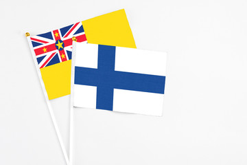 Finland and Niue stick flags on white background. High quality fabric, miniature national flag. Peaceful global concept.White floor for copy space.