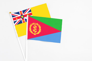 Eritrea and Niue stick flags on white background. High quality fabric, miniature national flag. Peaceful global concept.White floor for copy space.