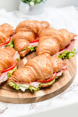 Sandwich croissant on a marble surface and wooden plate 