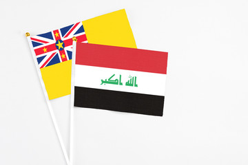 Iraq and Niue stick flags on white background. High quality fabric, miniature national flag. Peaceful global concept.White floor for copy space.