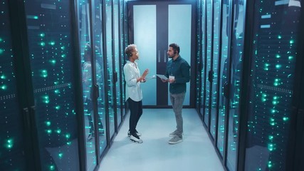 In futuristic server room multi-ethnic female and male IT specialists discussing work issues coworking. Professional team working at data center storage security.
