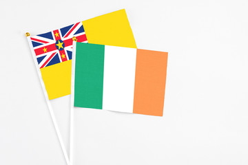 Ireland and Niue stick flags on white background. High quality fabric, miniature national flag. Peaceful global concept.White floor for copy space.