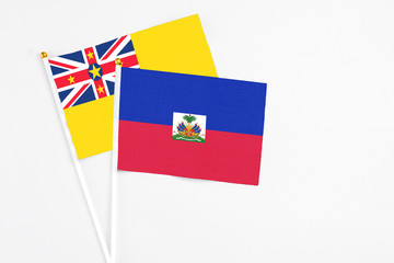 Haiti and Niue stick flags on white background. High quality fabric, miniature national flag. Peaceful global concept.White floor for copy space.