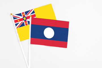 Laos and Niue stick flags on white background. High quality fabric, miniature national flag. Peaceful global concept.White floor for copy space.