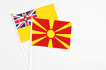 Macedonia and Niue stick flags on white background. High quality fabric, miniature national flag. Peaceful global concept.White floor for copy space.