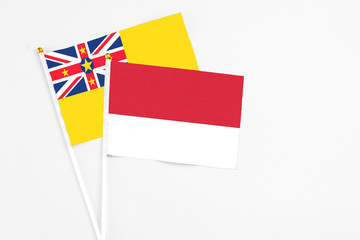 Monaco and Niue stick flags on white background. High quality fabric, miniature national flag. Peaceful global concept.White floor for copy space.