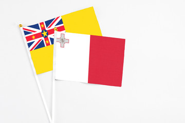 Malta and Niue stick flags on white background. High quality fabric, miniature national flag. Peaceful global concept.White floor for copy space.