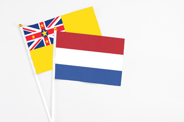 Netherlands and Niue stick flags on white background. High quality fabric, miniature national flag. Peaceful global concept.White floor for copy space.