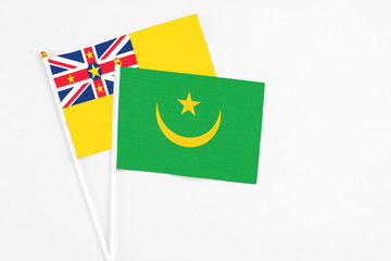 Mauritania and Niue stick flags on white background. High quality fabric, miniature national flag. Peaceful global concept.White floor for copy space.