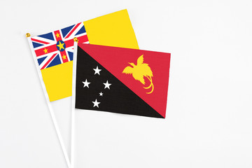 Papua New Guinea and Niue stick flags on white background. High quality fabric, miniature national flag. Peaceful global concept.White floor for copy space.