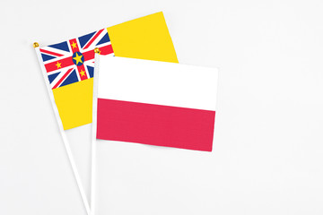 Poland and Niue stick flags on white background. High quality fabric, miniature national flag. Peaceful global concept.White floor for copy space.