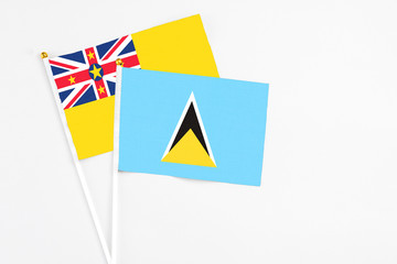 Saint Lucia and Niue stick flags on white background. High quality fabric, miniature national flag. Peaceful global concept.White floor for copy space.