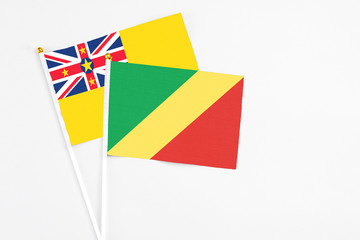 Republic Of The Congo and Niue stick flags on white background. High quality fabric, miniature national flag. Peaceful global concept.White floor for copy space.