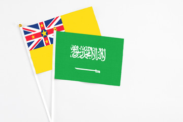 Saudi Arabia and Niue stick flags on white background. High quality fabric, miniature national flag. Peaceful global concept.White floor for copy space.