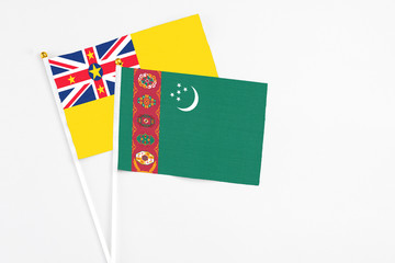Turkmenistan and Niue stick flags on white background. High quality fabric, miniature national flag. Peaceful global concept.White floor for copy space.