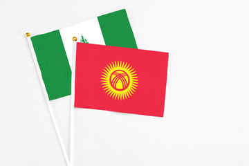 Kyrgyzstan and Norfolk Island stick flags on white background. High quality fabric, miniature national flag. Peaceful global concept.White floor for copy space.
