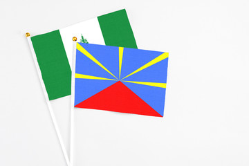 Reunion and Norfolk Island stick flags on white background. High quality fabric, miniature national flag. Peaceful global concept.White floor for copy space.