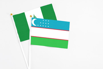 Uzbekistan and Norfolk Island stick flags on white background. High quality fabric, miniature national flag. Peaceful global concept.White floor for copy space.