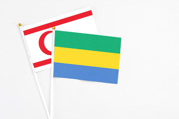 Gabon and Northern Cyprus stick flags on white background. High quality fabric, miniature national flag. Peaceful global concept.White floor for copy space.