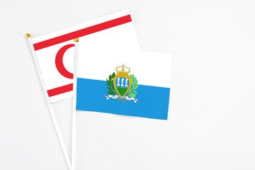 San Marino and Northern Cyprus stick flags on white background. High quality fabric, miniature national flag. Peaceful global concept.White floor for copy space.