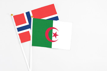 Algeria and Norway stick flags on white background. High quality fabric, miniature national flag. Peaceful global concept.White floor for copy space.