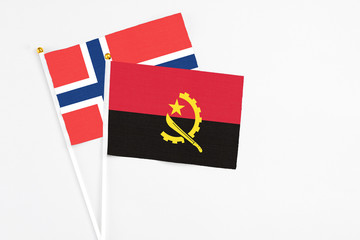 Angola and Norway stick flags on white background. High quality fabric, miniature national flag. Peaceful global concept.White floor for copy space.