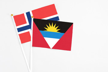 Antigua and Barbuda and Norway stick flags on white background. High quality fabric, miniature national flag. Peaceful global concept.White floor for copy space.