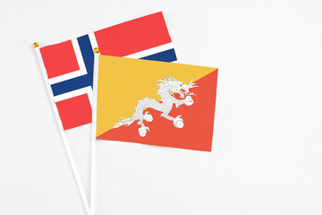Bhutan and Norway stick flags on white background. High quality fabric, miniature national flag. Peaceful global concept.White floor for copy space.
