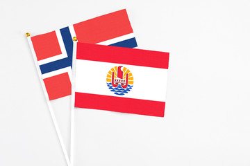 French Polynesia and Norway stick flags on white background. High quality fabric, miniature national flag. Peaceful global concept.White floor for copy space.