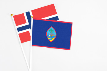 Guam and Norway stick flags on white background. High quality fabric, miniature national flag. Peaceful global concept.White floor for copy space.