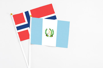 Guatemala and Norway stick flags on white background. High quality fabric, miniature national flag. Peaceful global concept.White floor for copy space.