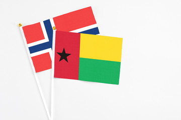 Guinea Bissau and Norway stick flags on white background. High quality fabric, miniature national flag. Peaceful global concept.White floor for copy space.