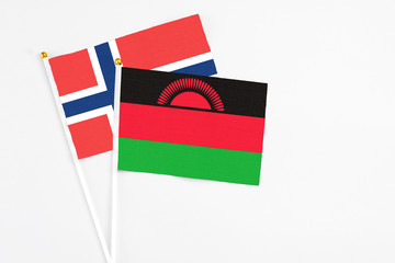 Malawi and Norway stick flags on white background. High quality fabric, miniature national flag. Peaceful global concept.White floor for copy space.