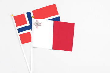 Malta and Norway stick flags on white background. High quality fabric, miniature national flag. Peaceful global concept.White floor for copy space.