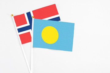 Palau and Norway stick flags on white background. High quality fabric, miniature national flag. Peaceful global concept.White floor for copy space.
