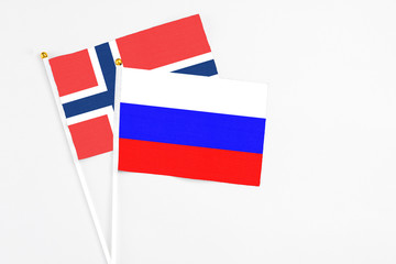 Russia and Norway stick flags on white background. High quality fabric, miniature national flag. Peaceful global concept.White floor for copy space.