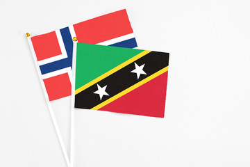 Saint Kitts And Nevis and Norway stick flags on white background. High quality fabric, miniature national flag. Peaceful global concept.White floor for copy space.