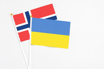 Ukraine and Norway stick flags on white background. High quality fabric, miniature national flag. Peaceful global concept.White floor for copy space.