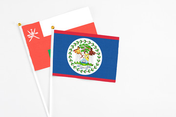 Belize and Oman stick flags on white background. High quality fabric, miniature national flag. Peaceful global concept.White floor for copy space.