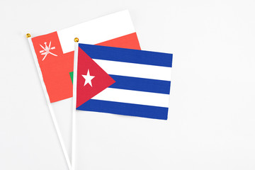 Cuba and Oman stick flags on white background. High quality fabric, miniature national flag. Peaceful global concept.White floor for copy space.
