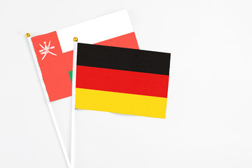 Germany and Oman stick flags on white background. High quality fabric, miniature national flag. Peaceful global concept.White floor for copy space.