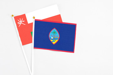 Guam and Oman stick flags on white background. High quality fabric, miniature national flag. Peaceful global concept.White floor for copy space.