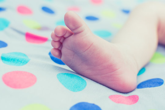 Foot of lying baby on polka dots blanket